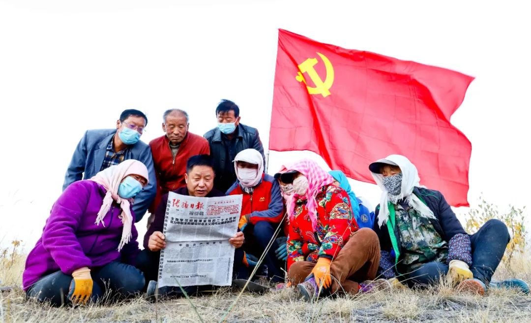 ↑2022年11月1日，甘肃省张掖市甘州区花寨乡秋季植树造林现场，党员干部同村民们在植树间隙认真学习党的二十大精神。