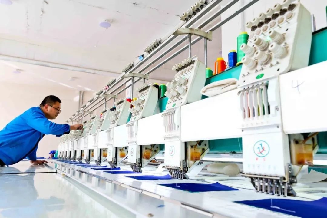 ↑2022年3月24日，甘肃省张掖市山丹县海兰达服饰乡村就业工厂内，技术人员调整绣花机器。五年前，山丹县海兰达服饰开办以服装、纺织品加工制作的“扶贫车间”，助力妇女走上脱贫致富路。
