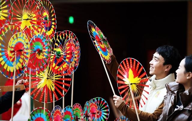 1月14日，人们在山东省临沂市“非物质文化遗产月”活动现场观赏民间艺人制作的风车。新华社发（张春雷摄）