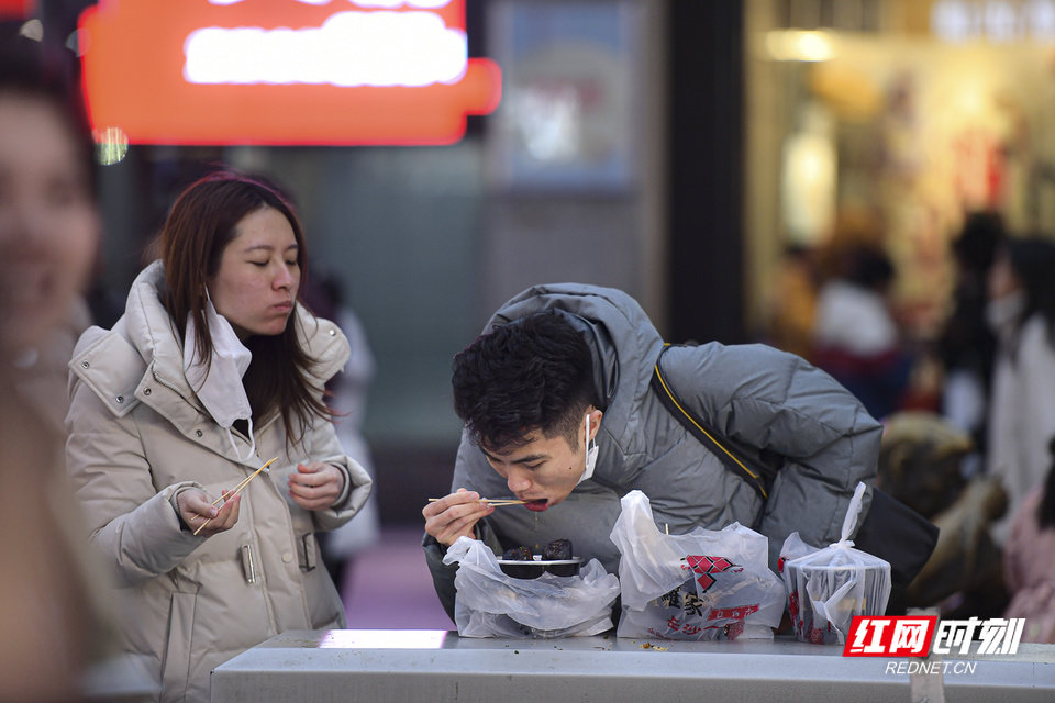 多数网红打卡店排队超过半小时，这对情侣取到“罗家臭豆腐”，迫不及待地品尝起来。