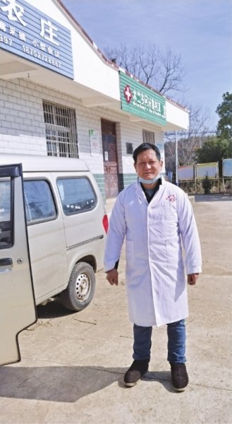 程劲松在村医务室门口，一旁是他的面包车。