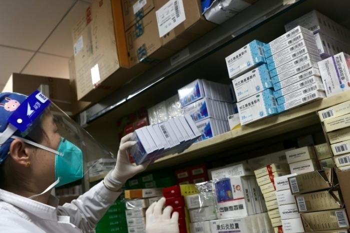 资料图:医务人员正将配送到的感冒药放入药架。 中新社记者 易海菲 摄