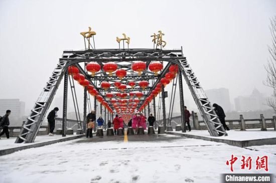 2月8日，兰州迎来立春后首场降雪，图为游客在当地标志性建筑中山桥上“打卡”。　李亚龙　摄