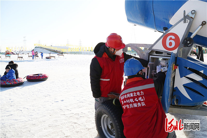 国网冀北电力唐山“钢铁之魂”共产党员服务队队员在检查造雪机用电设备。通讯员石向奎摄.jpg