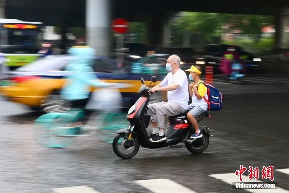 资料图：家长骑车送学生返校上课。中新社记者 易海菲 摄