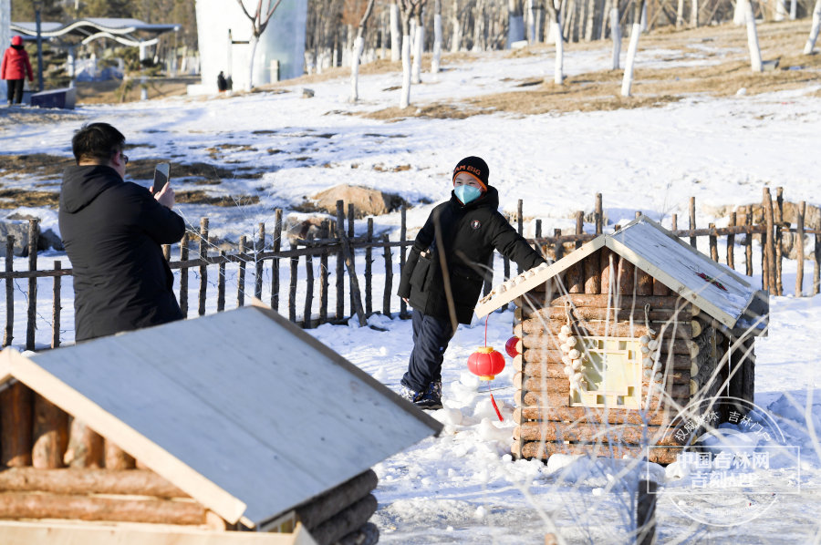小朋友与低于自己的木屋合影留念。
