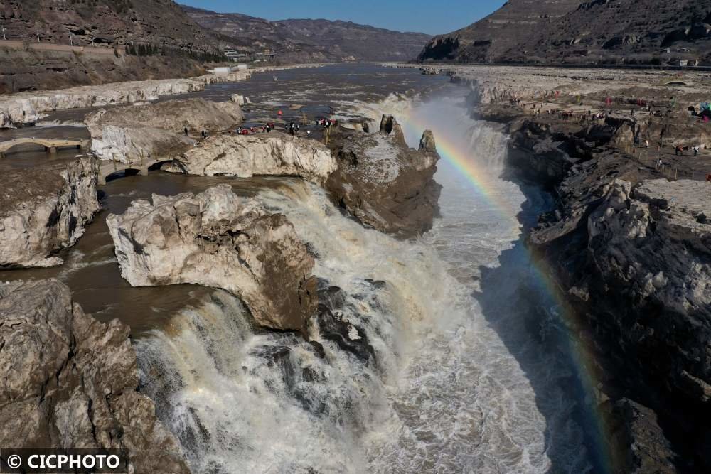 ↑2023年2月19日,游客在山西省临汾市吉县黄河壶口瀑布景区欣赏“彩虹通天”景观。近日,位于晋陕大峡谷之间的黄河壶口瀑布冰凌消融,水量增大。(无人机照片)CICPHOTO/吕桂明 摄