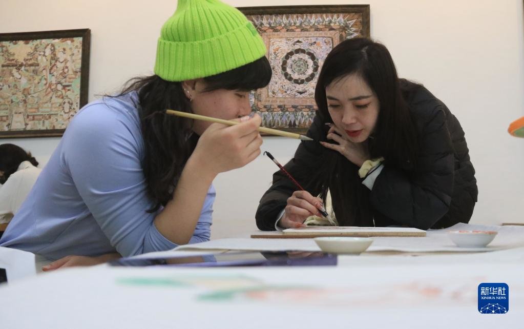 2月23日，在敦煌研究院莫高学堂，研学导师（右）指导学员临摹敦煌壁画。新华社发（张晓亮 摄）