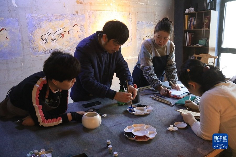 2月22日，在敦煌小镇鸣沙书院，艺术工作者张杰龙（中）指导学员进行颜料调色。新华社发（张晓亮 摄）