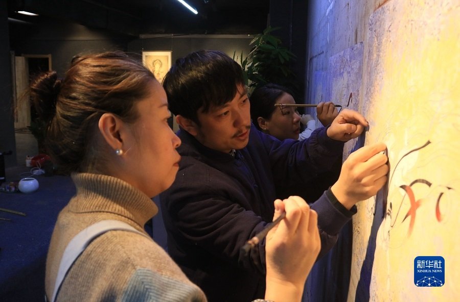 2月22日，在敦煌小镇鸣沙书院，艺术工作者张杰龙（中）指导学员临摹敦煌壁画。新华社发（张晓亮 摄）
