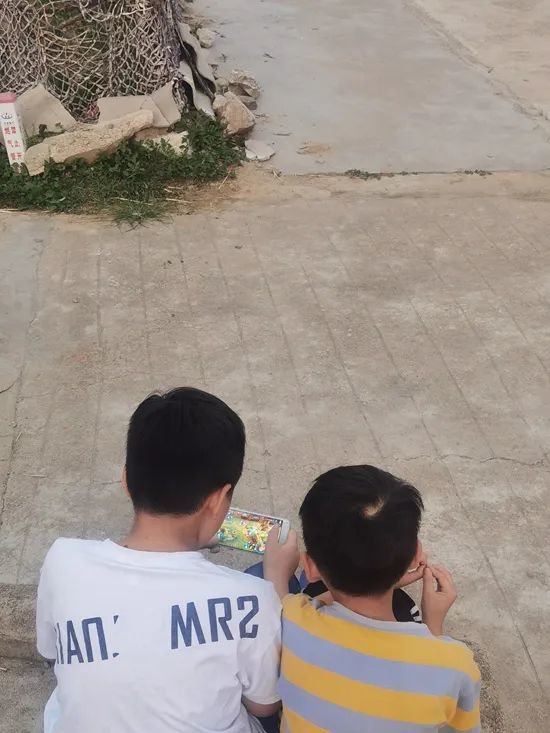 中部省份某村庄,两名男孩聚在一起玩手机游戏。