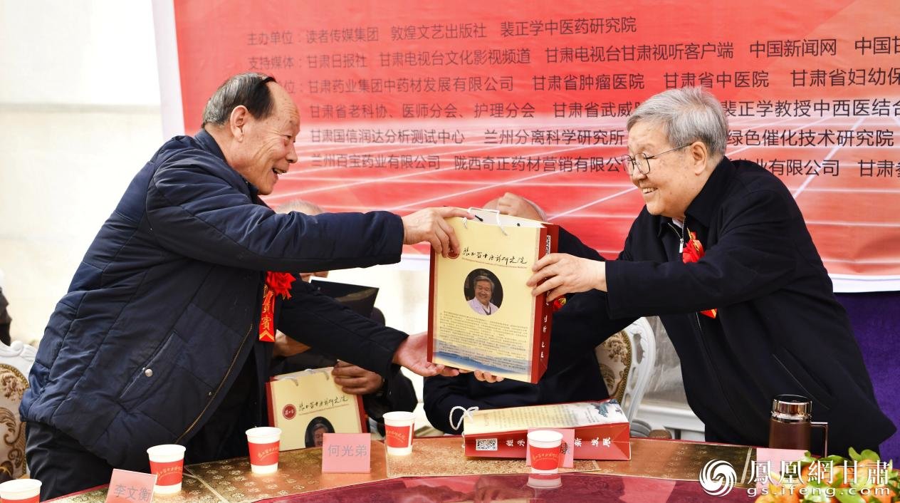 裴正学（右）在发布会现场赠书 马斌 摄