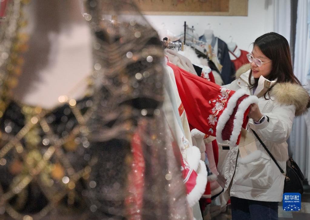 游客在洛阳市洛邑古城的传统服饰店内挑选服装（2月22日摄）。新华社记者 李安 摄