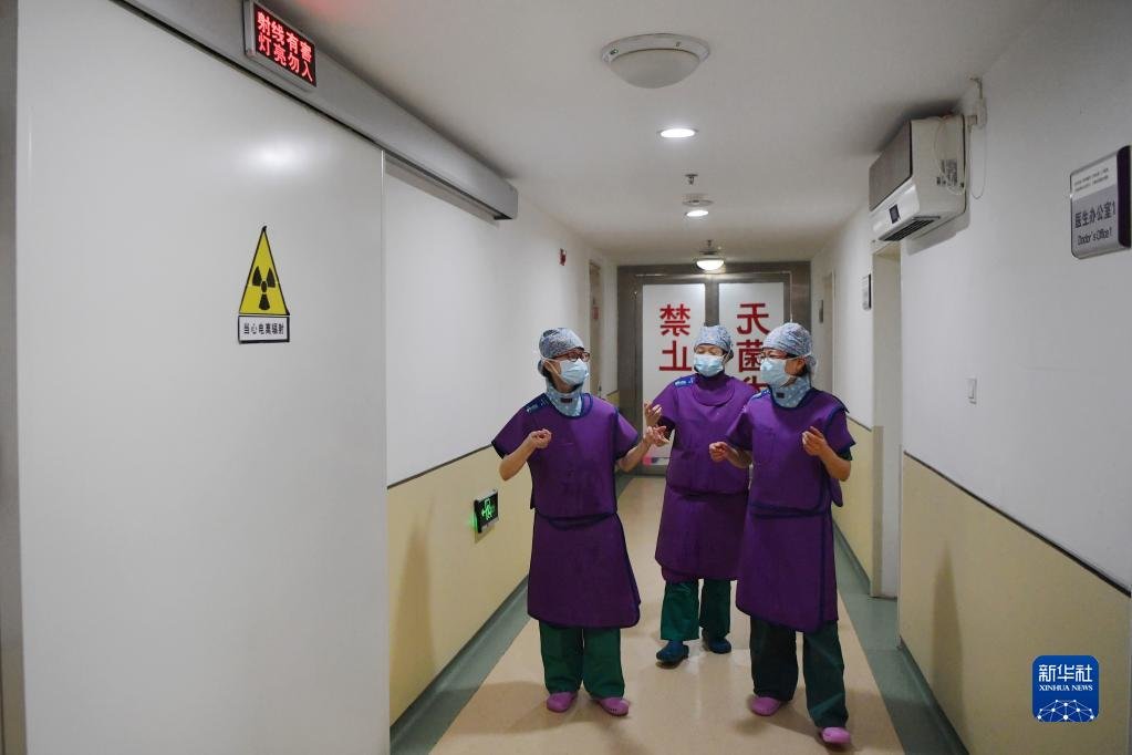 3月6日,穿上铅衣的马娜(左一)和同事准备进入手术室。新华社记者 陈斌 摄