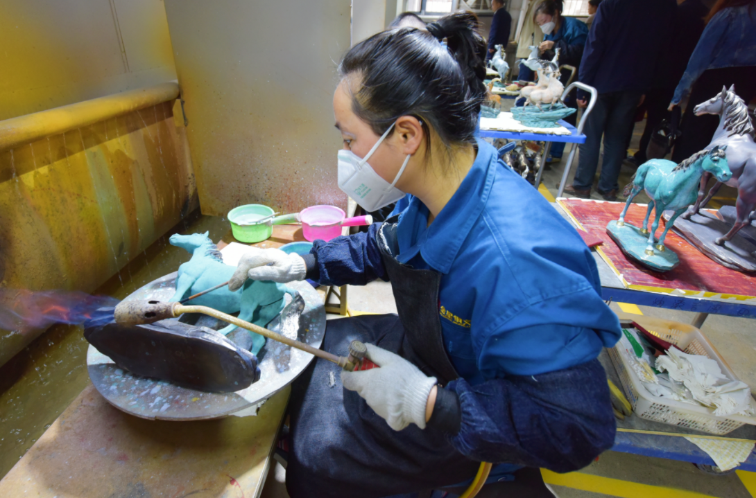 图为手工匠人正用“焚失法”铸铜技艺进行着色处理。