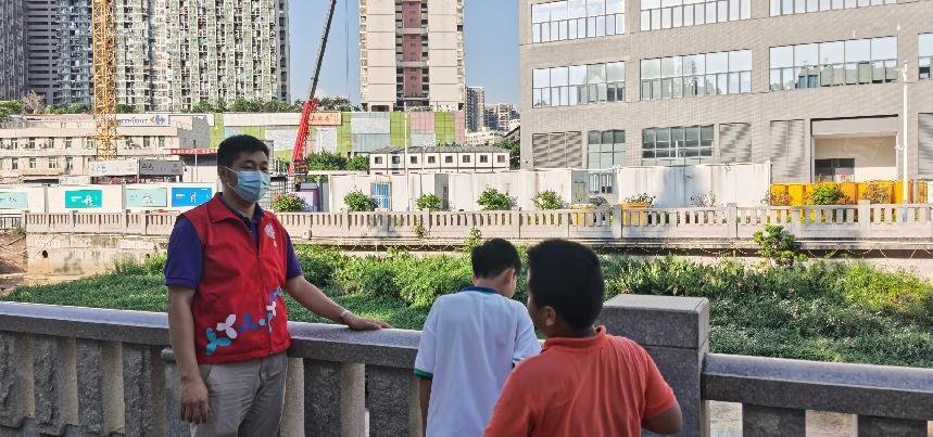 志愿者正在劝导河边玩耍孩童