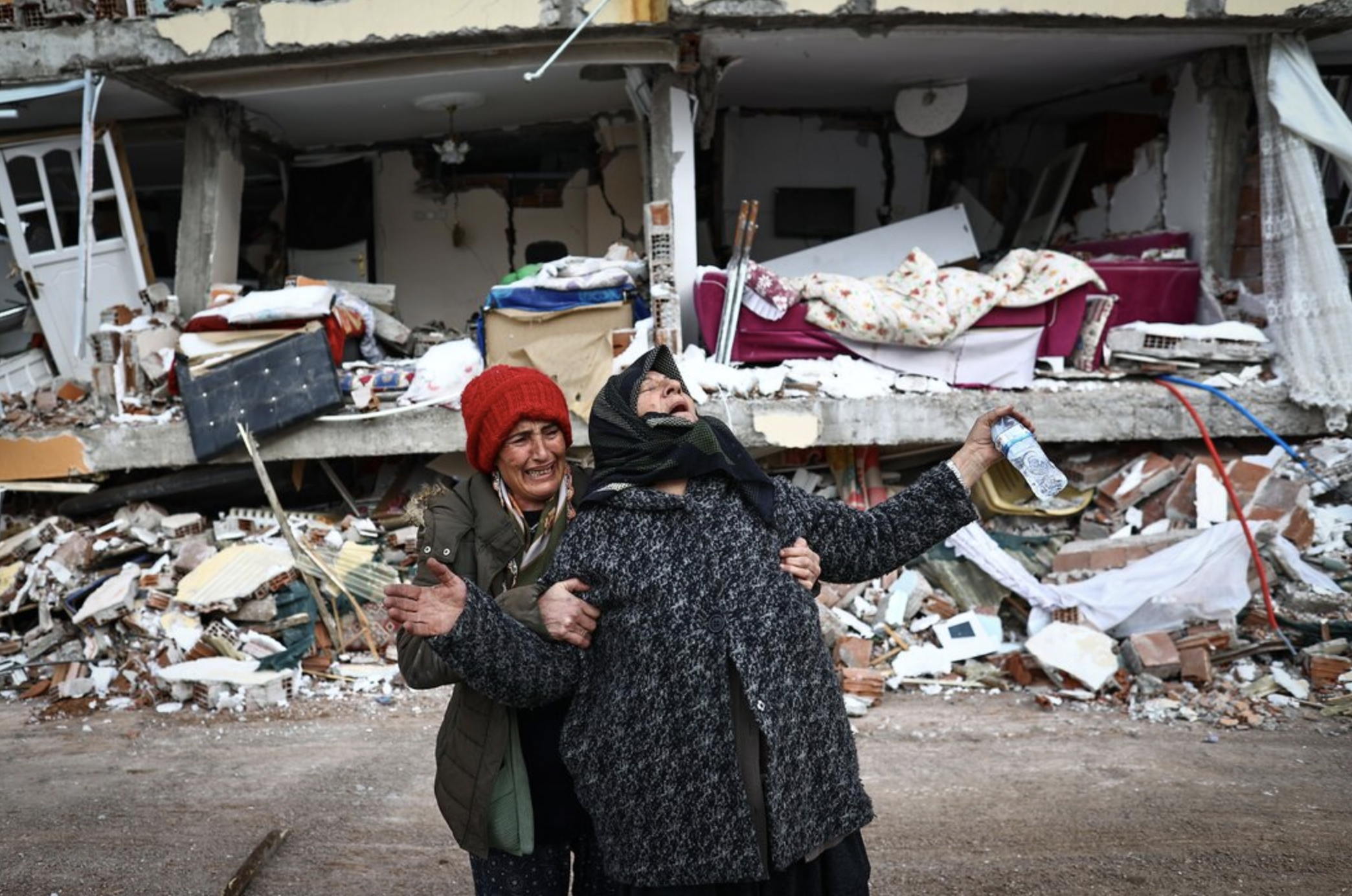 2月，土耳其埃尔比斯坦地区发生大地震后，女人们在一座倒塌的建筑前。