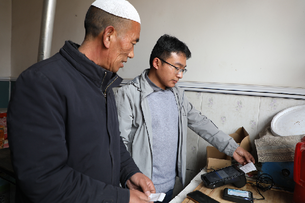 甘肃省临夏回族自治州东乡族自治县大树乡米家村的米么万三家，东乡县供排水服务中心工作人员使用微信收费终端上门收取水费。新华每日电讯记者 多蕾 摄