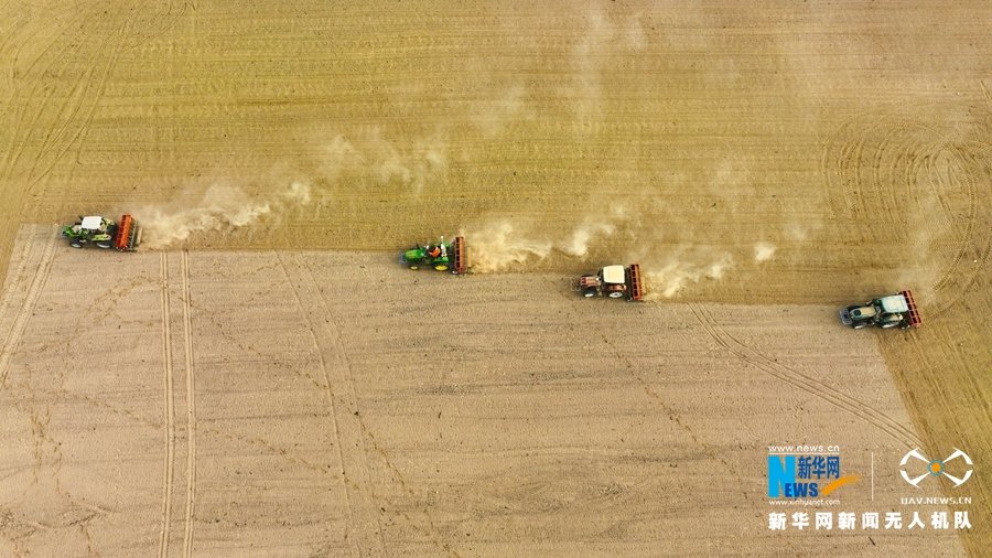 甘肃省张掖市民乐县民联镇高寨村小麦种植基地，大型机械正在播种小麦。新华网发（张学爱 摄）