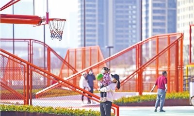 杨泗港都市T台的篮球场上市民带着孩子在暖阳下打起篮球。