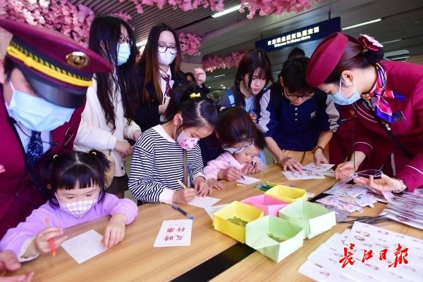 乘客积极参与“樱你而来”樱花季活动，现场书写祝福卡片，获赠手绘樱花书签。记者李永刚 摄