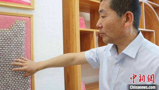 图为高伟展示用易拉罐拉环制作的“锁子甲”。李文华 摄