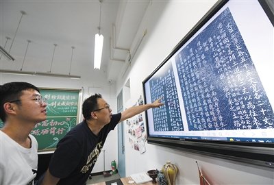 北京建筑大学教师董友强（左二）和学生一起观察石碑的数字拓片。