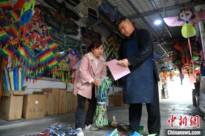 “金鸡风筝扎制技艺”传承人高加辉(右一)正在清点风筝订单。 王磊 摄