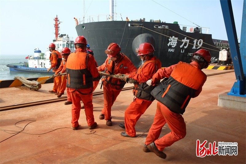 在河北港口集团黄骅港综合港区，工人们在为靠泊轮船系缆绳。