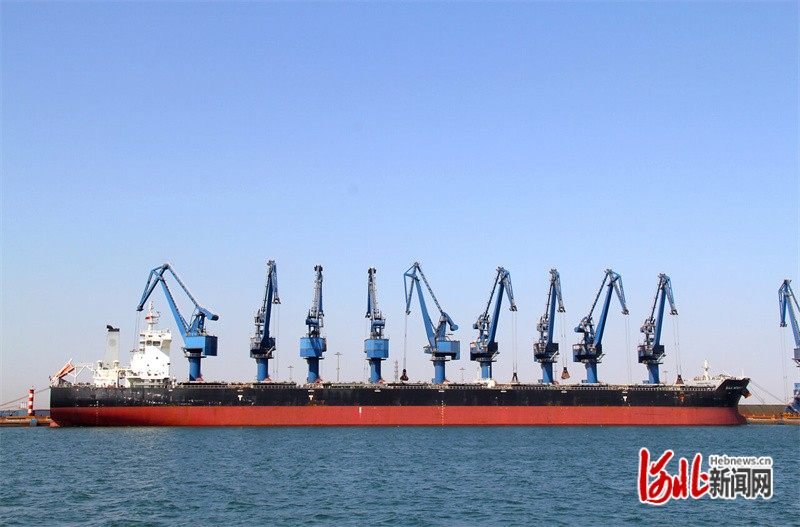河北港口集团曹妃甸港区，货船停泊在码头进行装船作业。