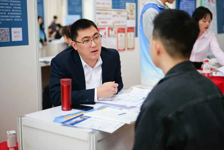 招聘会现场，企业与准毕业生交流。