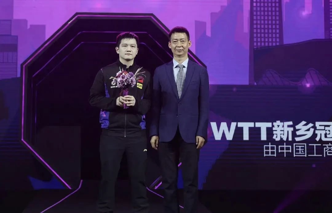 ▲朱俊峰为男单冠军樊振东颁发鲜花并合影