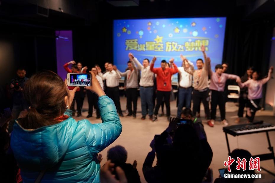 资料图:一名孤独症患者的家人拍摄现场文艺表演。中新社记者 崔楠 摄