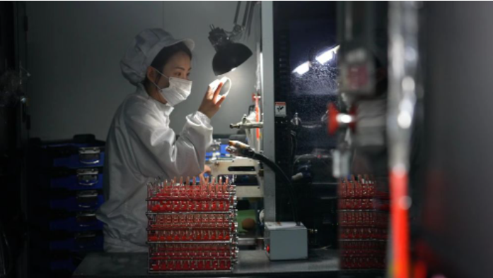 在万新光学集团的定制镜片车房加工中心,工人在进行镜片合模工序。