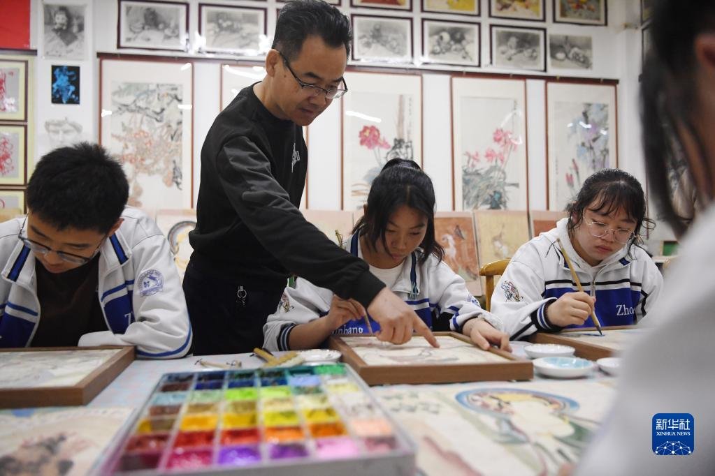 4月26日，敦煌中学美术教师王玉林（左二）指导学生临摹敦煌壁画。