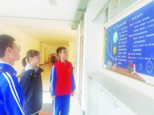 江西师范大学附属中学滨江校区高一12班学生(右一)王庆博向参观的学生介绍学校