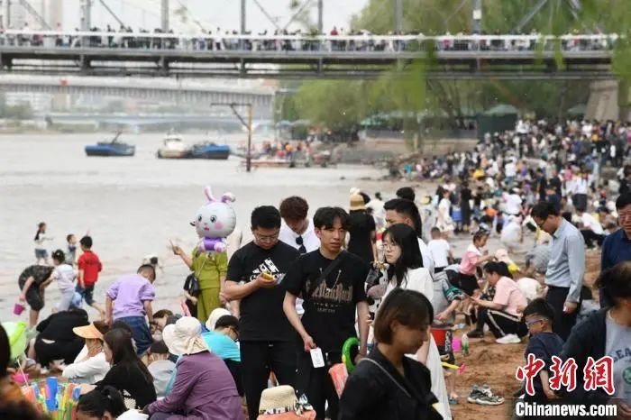 图为游客在黄河岸边游玩，远处的中山桥游人如织。　戴文昌 摄