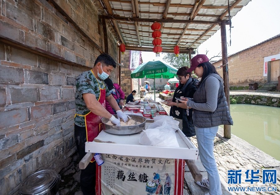 在双塘镇竹桥古村，游客正在购买当地特色小吃。新华网发 邓兴东 摄