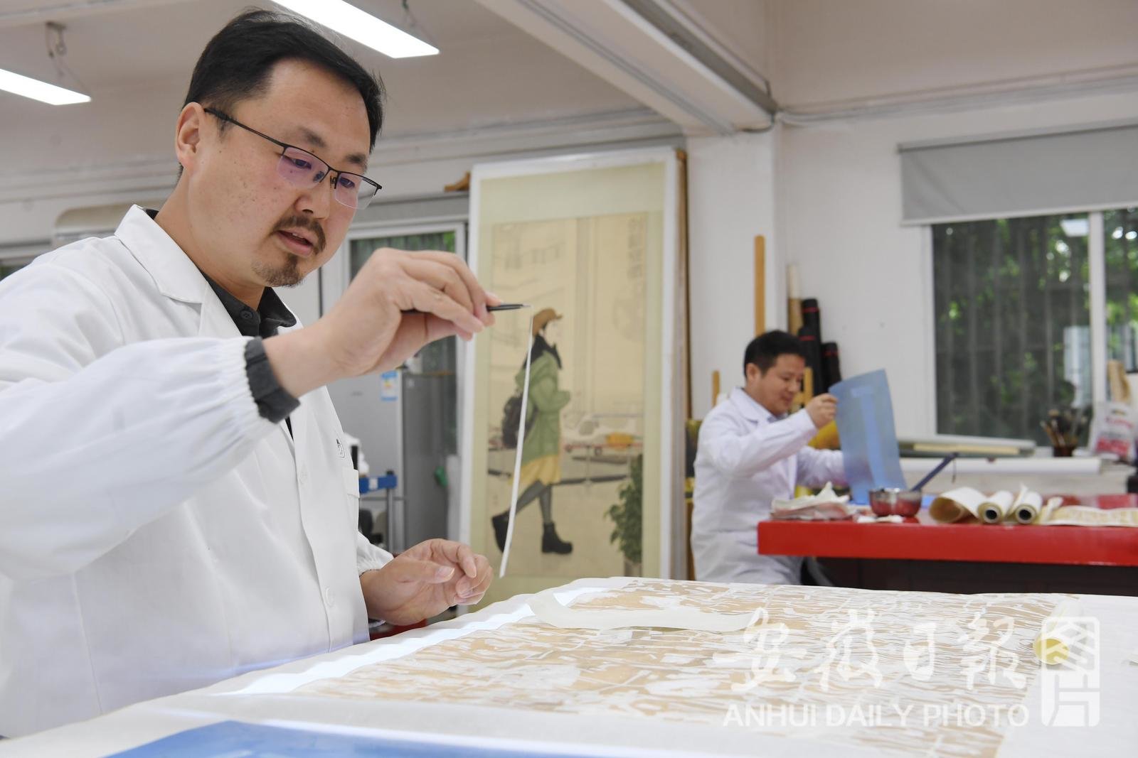 4月25日，在省博物院文物科技保护中心书画修复室，42岁的王时运修复（左）清代王琏的人物堂轴。
