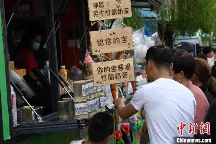 图为游客在中山桥旁边的便利店购买竹筒奶茶 戴文昌 摄