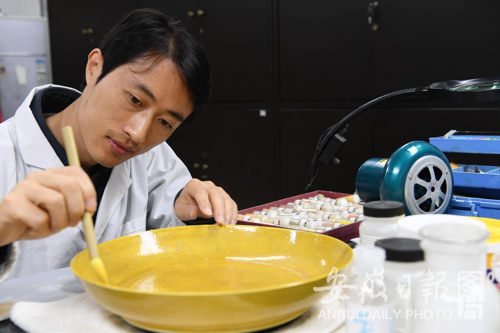 4月25日，在省博物院文物科技保护中心陶瓷修复室，39岁的朱善银修复“储秀宫制”黄釉刻花龙纹大盘。
