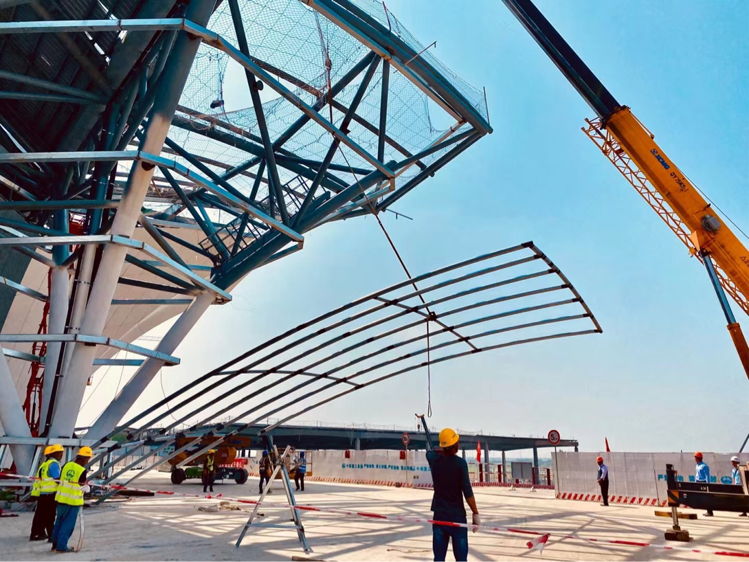 施工工人用塔吊机器将外立面金属装饰固定并焊接