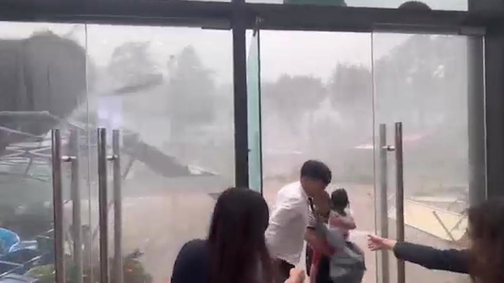 狂风暴雨中女子抱孩子无法行走,工作人员开门招呼进屋躲雨_凤凰网视频_凤凰网
