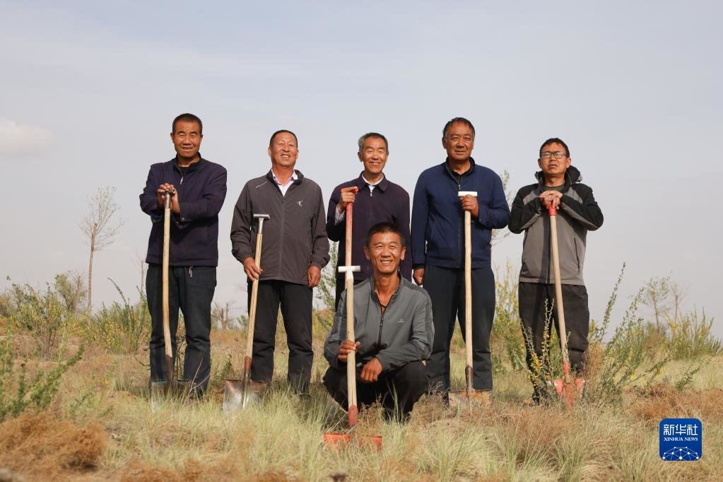 5月6日，八步沙两代治沙人在古浪县的一片治沙区劳作后合影留念。他们从左至右分别为：罗兴全（后左一）、石银山（后左二）、郭万刚（后中）、贺中强（后右二）、程生学（后右一）、郭玺（前）。新华社记者 马希平 摄