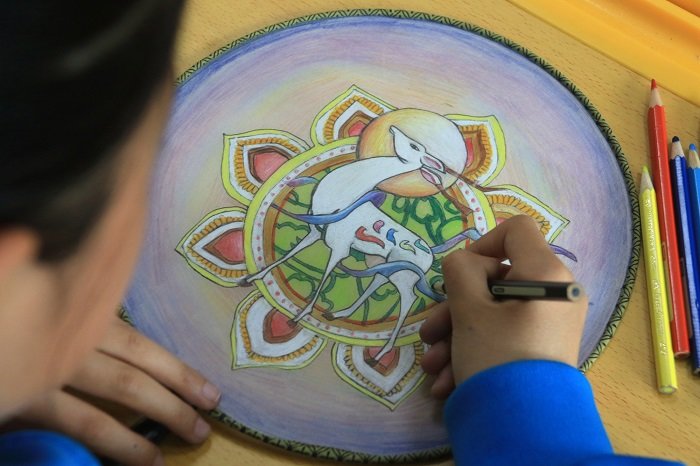 美术社团的学生在课后服务时间进行带有敦煌壁画元素的团扇绘画