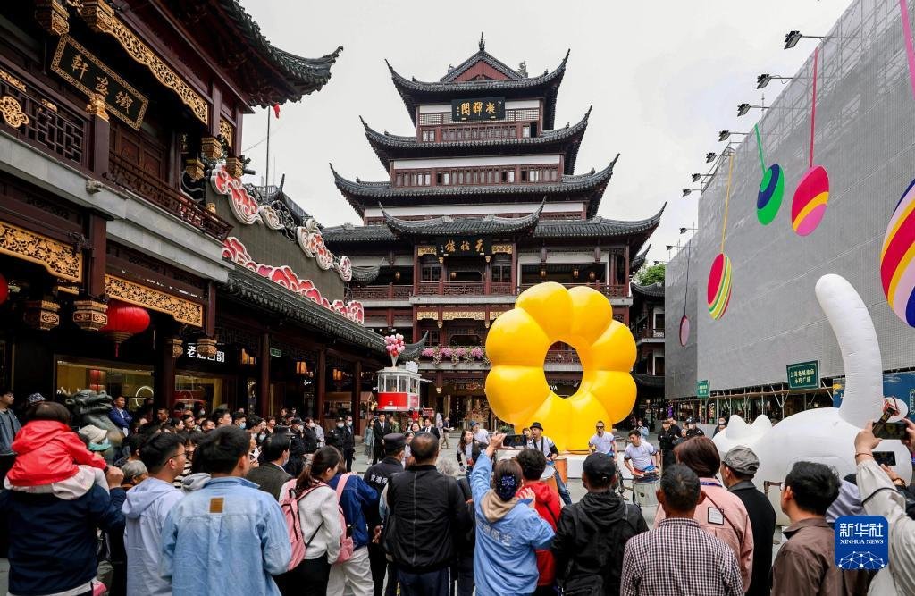 5月7日，市民游客在上海豫园商城中心广场观看街头艺术表演。新华社记者 刘颖 摄