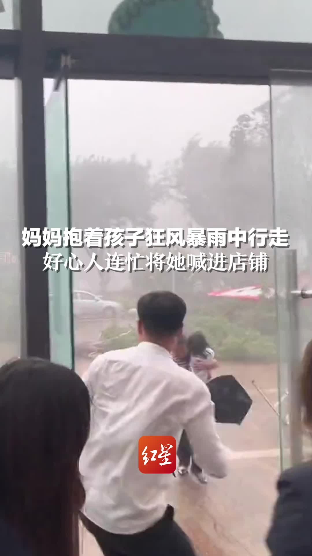 妈妈抱着孩子狂风暴雨中行走，好心人连忙将她喊进店铺