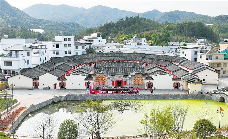 半月形的外围房舍和围前水塘，组合成一座蕴含团圆之意的客家围龙屋建筑群。