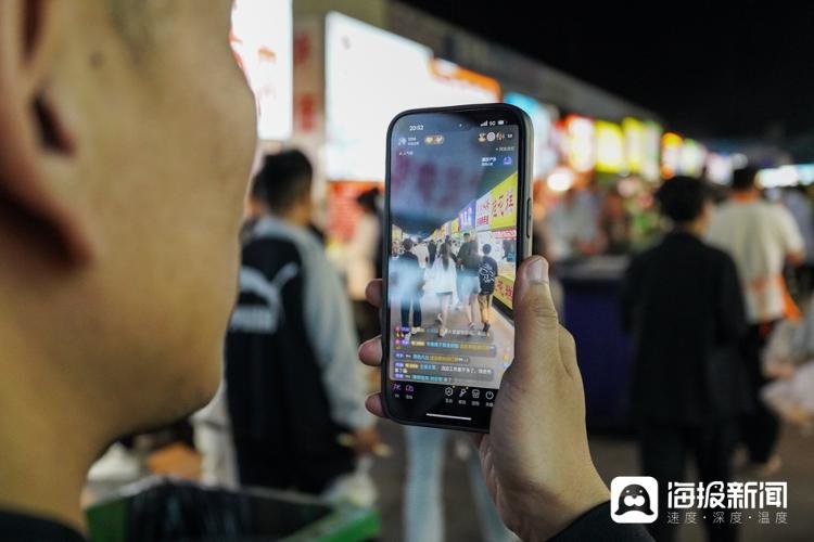 图:为了宣传夜市,以往谢伟会邀请一些网红前来直播,到后来谢伟索性自己上号直播,带领网友“云逛”夜市,亲自介绍夜市上的好品,几个月时间,他已经拥有了十几万粉丝,也吸引了不少人来夜市实地品尝。(海报新闻记者 毕胜 摄)