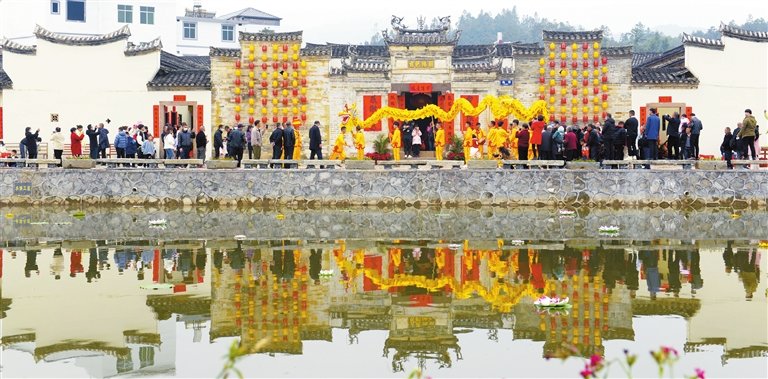 围龙屋前闹新春，游动的长龙与水中的倒影相映成趣。